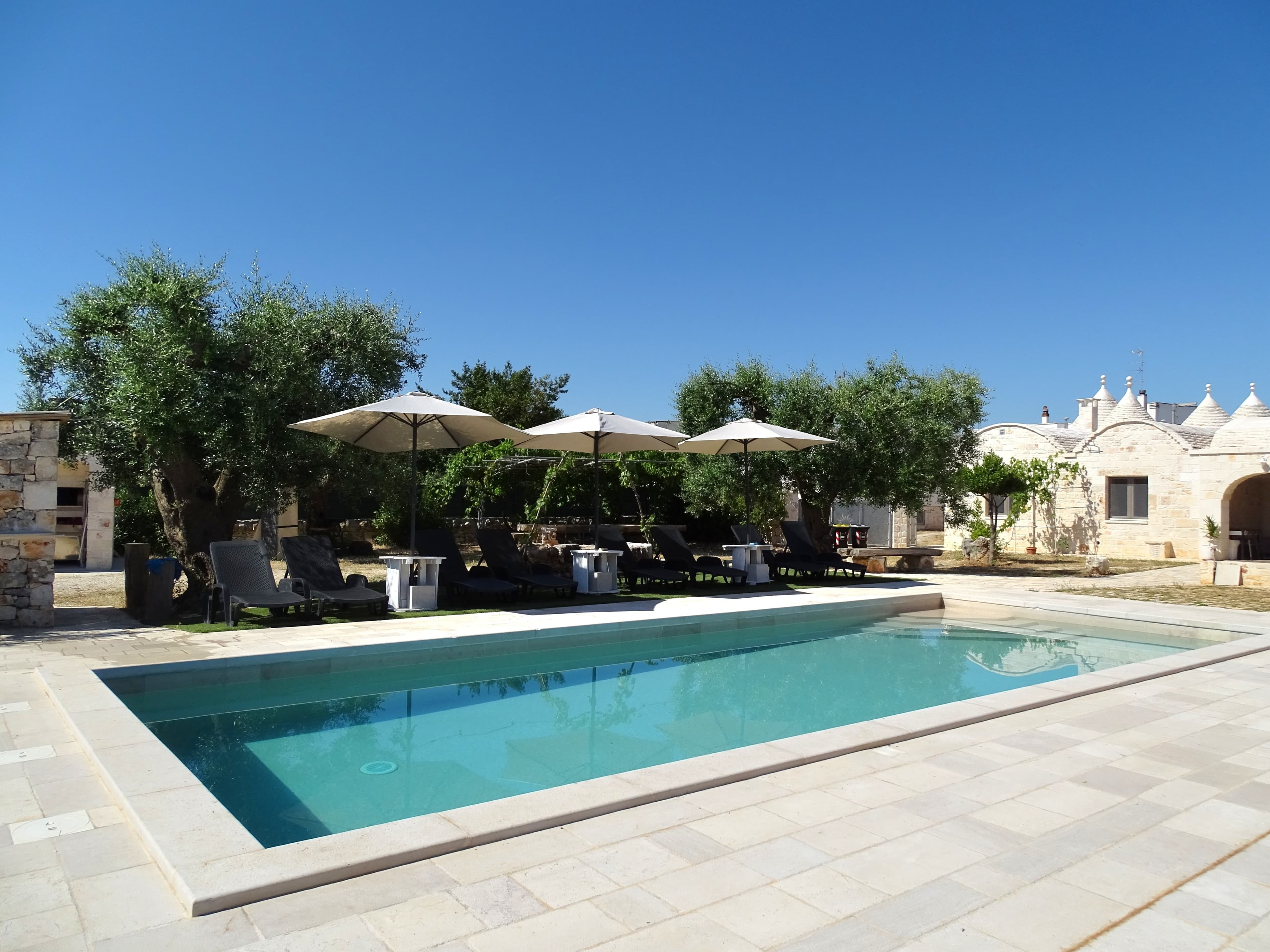 Piscina con lettini e ombrelloni sotto il cielo estivo